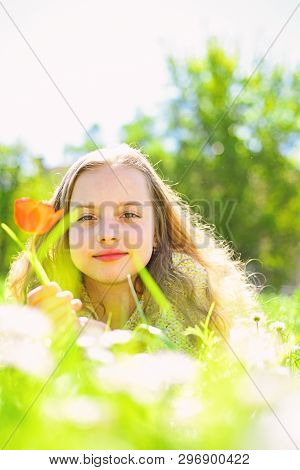 Girl Lying On Grass, Nature On Background, Defocused. Child Enjoy Spring Sunny Day While Lying At Me