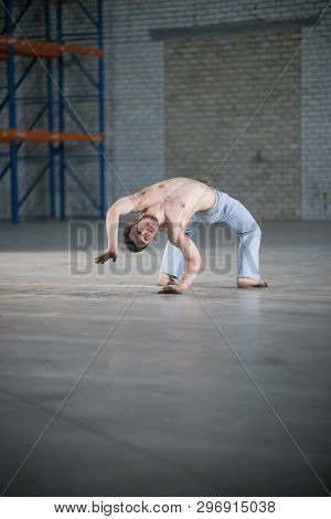 An Athletic Man On Capoeira Training. Standing On The Bending Over Backwards Position
