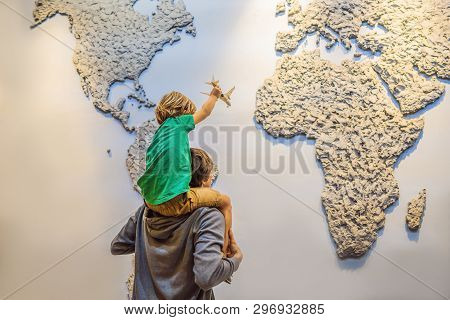 Dad And Son On The Background Of A World Map With An Airplane In His Hands. Travel Concept
