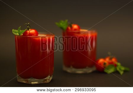 Two Glasses Of Tomato Juice With Cherry Tomatoes And Mint With A Black Background