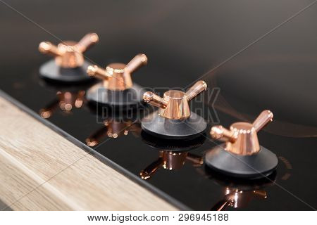 Closeup Of The Copper Knob Switch Plates Are Reflected In The Black Shiny Electric Or Gas Hob For Th