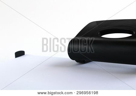 Black Office Puncher Isolated On White Background. Shit Of Paper In Hole Puncher.