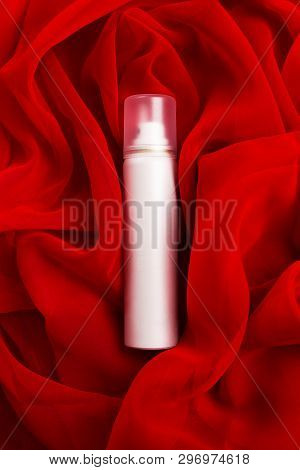 Beauty Spray (aerosol) Over Red Vapory And Wavy Cloth Background. Studio Shot