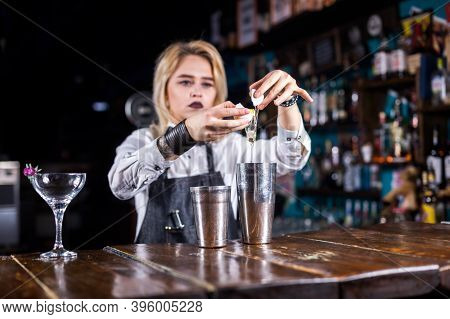 Pretty Girl Bartending Makes A Cocktail While Standing Near The Bar Counter In Nightclub