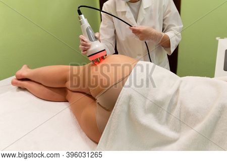 The Beautician Performs The Rf-lifting Procedure On The Thigh Of A Young Woman. Leads The Maniple On