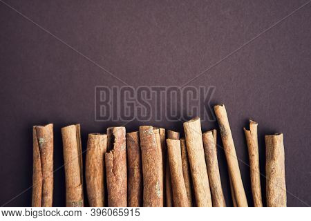 Cinnamon Sticks On The Dark Brown, Chocolate Background With Copy Space For Your Text
