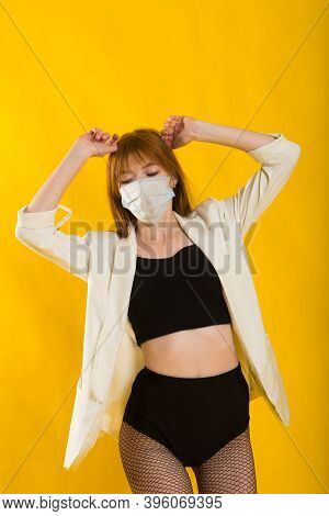 Female Strip Dancer In Yellow Studio In Protective Mask From Covid
