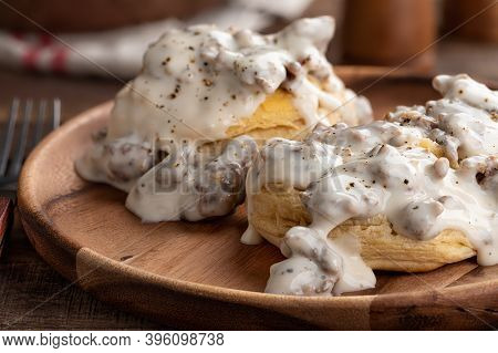 Closeup Of Biscuits And Creamy Sausage Gravy On A Wooden Plate