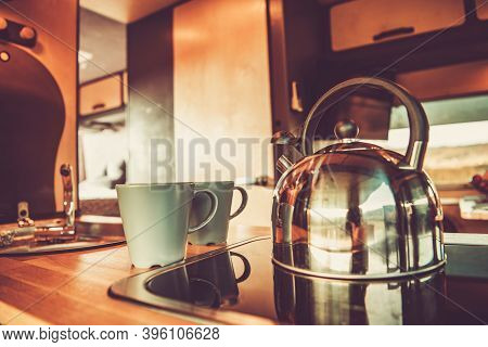 Shiny Metal Water Kettle And Two Cups With Hot Tea Inside Rv Camper Van Kitchen Area. Recreational V