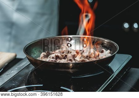 The Chef Cooks The Small Octopus On A Metal Frying Pan