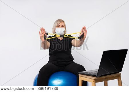 Senior Woman Wearing Mask Holds Resistance Band Showing Stop Coronavirus.