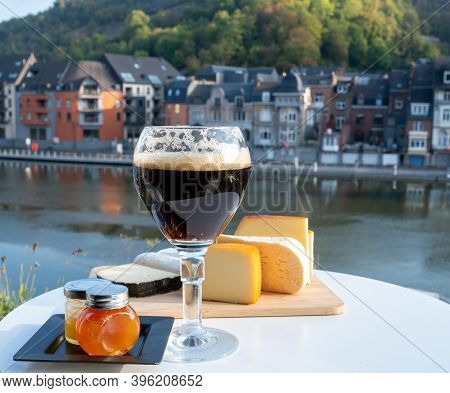 Drinking Of Dark And Strong Belgian Abbey Beer With Cheeses With Nice View On Maas River And Town Di