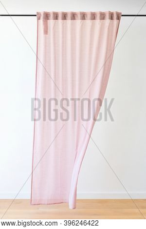 Pink drapery curtain hanging from a curtain rod