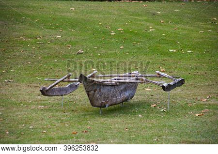 Old Wooden Boat, Trimaran, On A Field Among Green Grass
