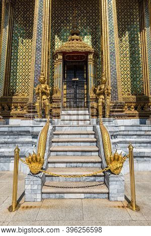 Bangkok, Thailand - December 7, 2019: View Of The Golden Giant Statues Guarding Massive Door To Phra