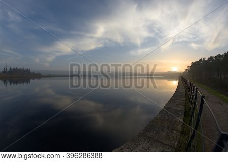 Sunset And Clouds Reflected In The Water Of Redmires Reservoir Near Sheffield. Level Horizon, But Fi