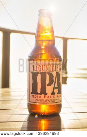 Lagunitas Ipa India Pale Ale Beer Bottle Against Strong Sunlight. Wooden Table.