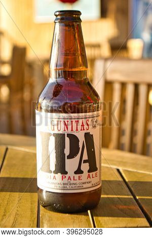 Lagunitas Ipa India Pale Ale Beer Bottle Against Strong Sunlight. Wooden Table.