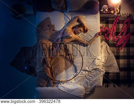 Action In A Dream . Top View Of Young Professional Rhythmic Gymnast Sleeping At Bed In Sportwear Wit