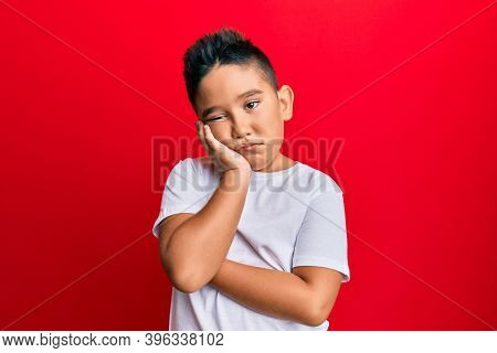 Little boy hispanic kid wearing casual white tshirt thinking looking tired and bored with depression problems with crossed arms. 