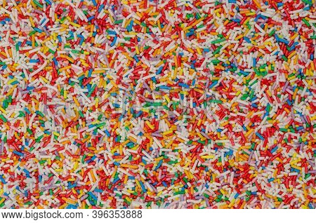Rainbow Sprinkles, Background And Surface. Rod-shaped Colorful Sugar Sprinkles. Tiny Candies In A Va