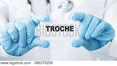 Doctor's Hands In Blue Gloves Shows The Word Troche. Medical Concept.