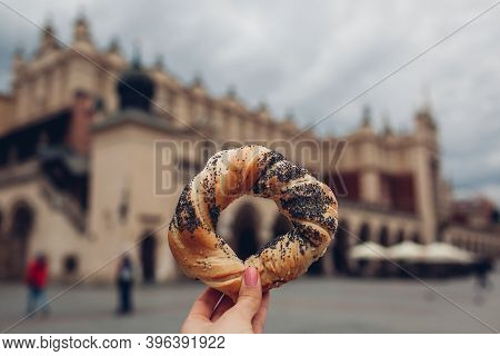 Tourists Holding Bagel Obwarzanek Traditional Polish Cuisine Snack On Market Square In Krakow. Trave