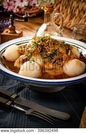 Dumplings With Turkey And Chorizo Sauce In A Painted Bowl.