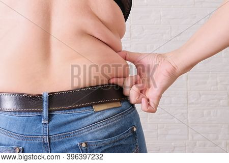 Young Woman Pinches The Fat On The Side Of Her Waist To Show The Flab, Overweighted Fat Body