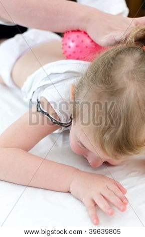 Masajista haciendo masaje a niña con una bola