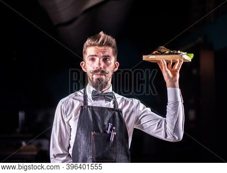 Charismatic Steward Helpfully Holds Plate With Prepared Dish At A Festive Event.