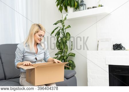 Transportation, Post And People Concept - Smiling Young Woman Opening Cardboard Box At Home