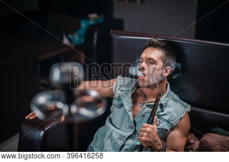 Man Smokes A Fragrant Oriental Hookah In The Shisha Hose.