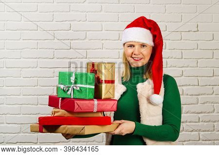 Wwoman In Red Hat Holding Many Christmas Gifts. Woman Holding A Lot Of Boxes With Gifts