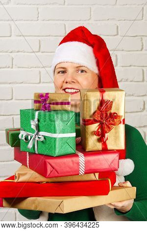 Wwoman In Red Hat Holding Many Christmas Gifts. Woman Holding A Lot Of Boxes With Gifts