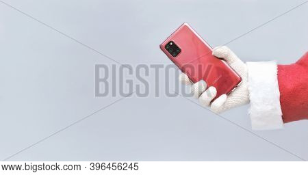 Santa Holding A Smartphone As A Holiday Gift. Samsung A31 Phone In Red Color. Call Santa Concept. Co