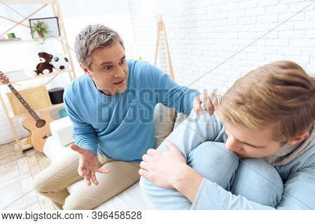 Father Sitting Near On Couch, Tries To Talk To His Son, But Problem Teenager Doesn't Want To Listen.