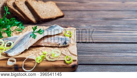 Herring Fillet With Parsley And Onion On A Cutting Board, Close-up, Dark Wooden Background. Traditio