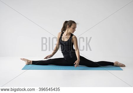 Young Woman Is Practicing Yoga In A Studio. Slim Young Girl In A Black Sport Wear Is Doing Yoga Prac