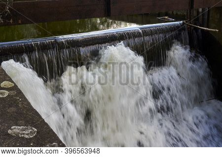 Overflow Of Water Over The Dam On A Sunny Day