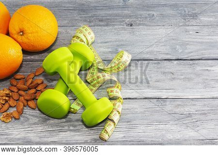 Lots Of Oranges, Dumbbells, Measuring Tape On A Wooden Textured Background. Fitness, Sports Nutritio