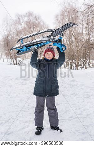 Teenager Boy With Sleigh In Hands In The Park In Winter. Active Lifestyle.