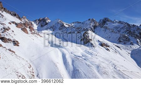 Snow Mountain Peaks With Rocks. View From Drone. In Places, You Can See Glaciers, Large Rocks And Ro