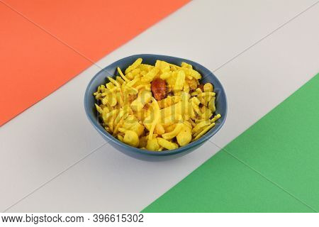 Sweet And Sour Indian Snack Of Noodles, Peanuts, Puffed Rice And Peas In Blue Snack Bowl On Orange, 