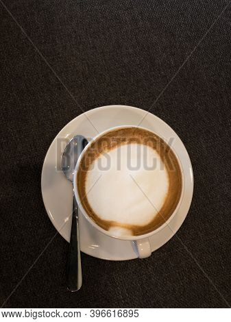 Coffee In White And Stanless Spoon On Black Fabric Background.copy Space.