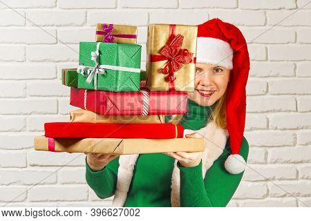 Wwoman In Red Hat Holding Many Christmas Gifts. Woman Holding A Lot Of Boxes With Gifts