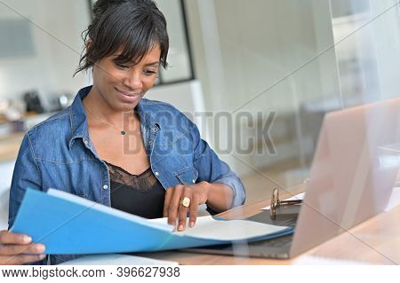 Office worker woman in open space area, protected by plexiglas