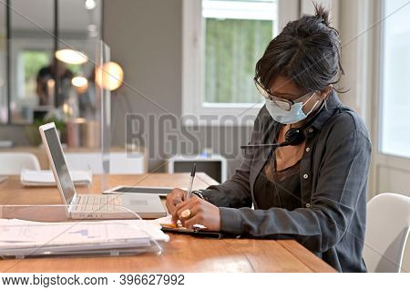 Office worker wearing surgical face mask in open space area