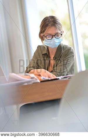 Office worker wearing surgical face mask in open space area