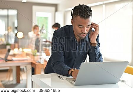 Salesman in co-working office with headsst working on laptop in open space office